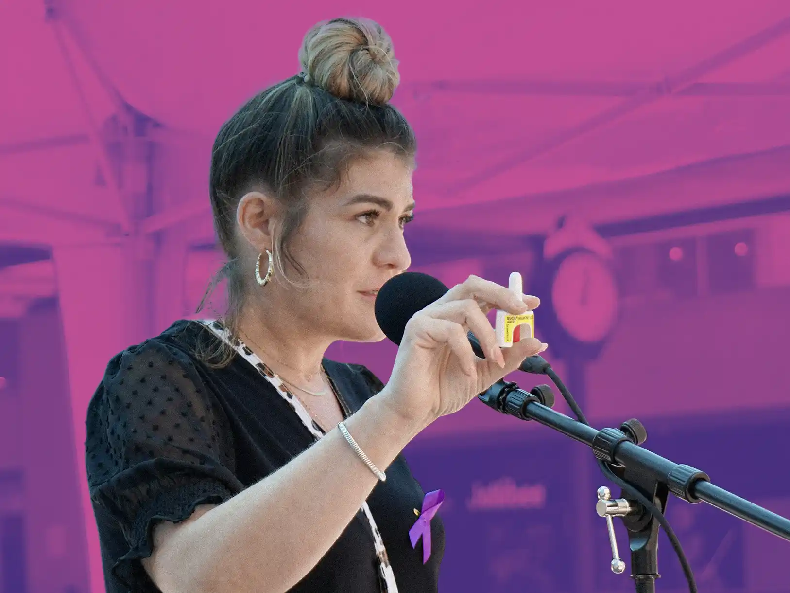 Woman speaking into a microphone and holding up a dose of Narcan