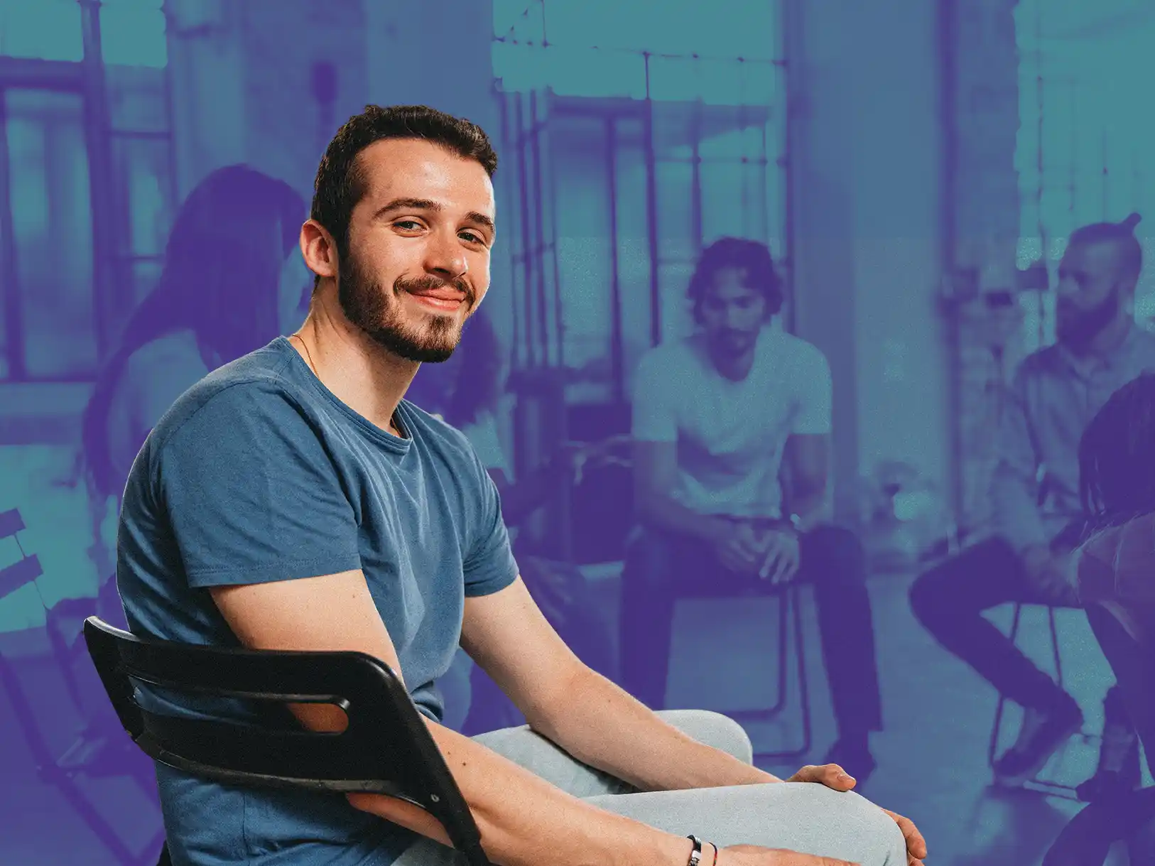 Young man attending a group recovery meeting and smiling