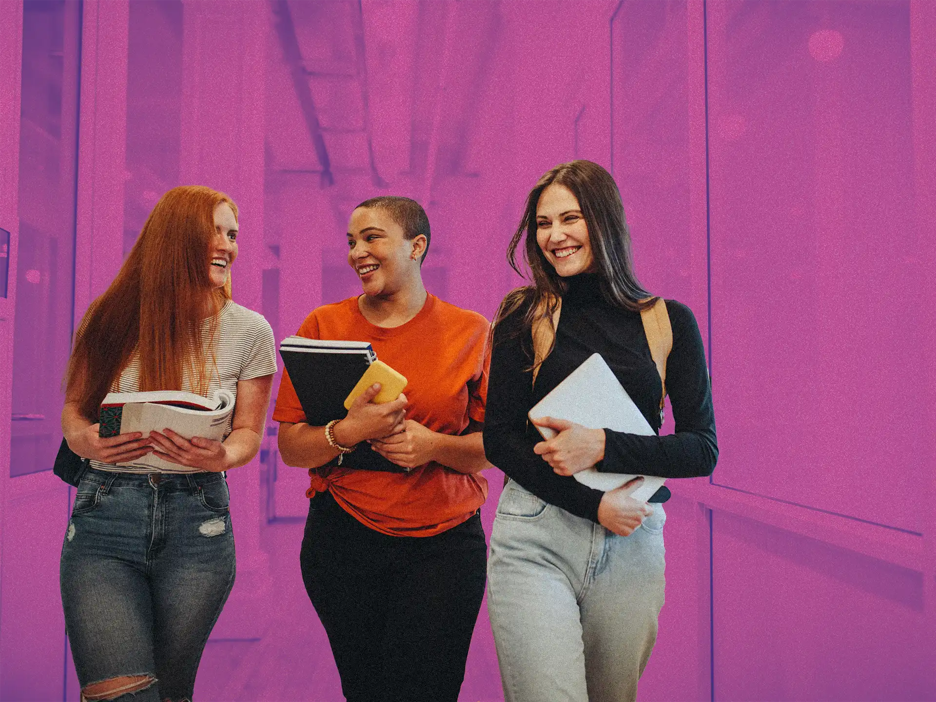 three young women with books in their arms walking down the hallway in school