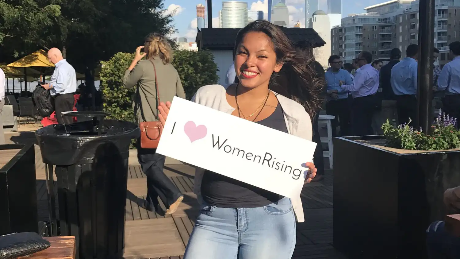 young woman holding a sign that says "I heart women rising!"