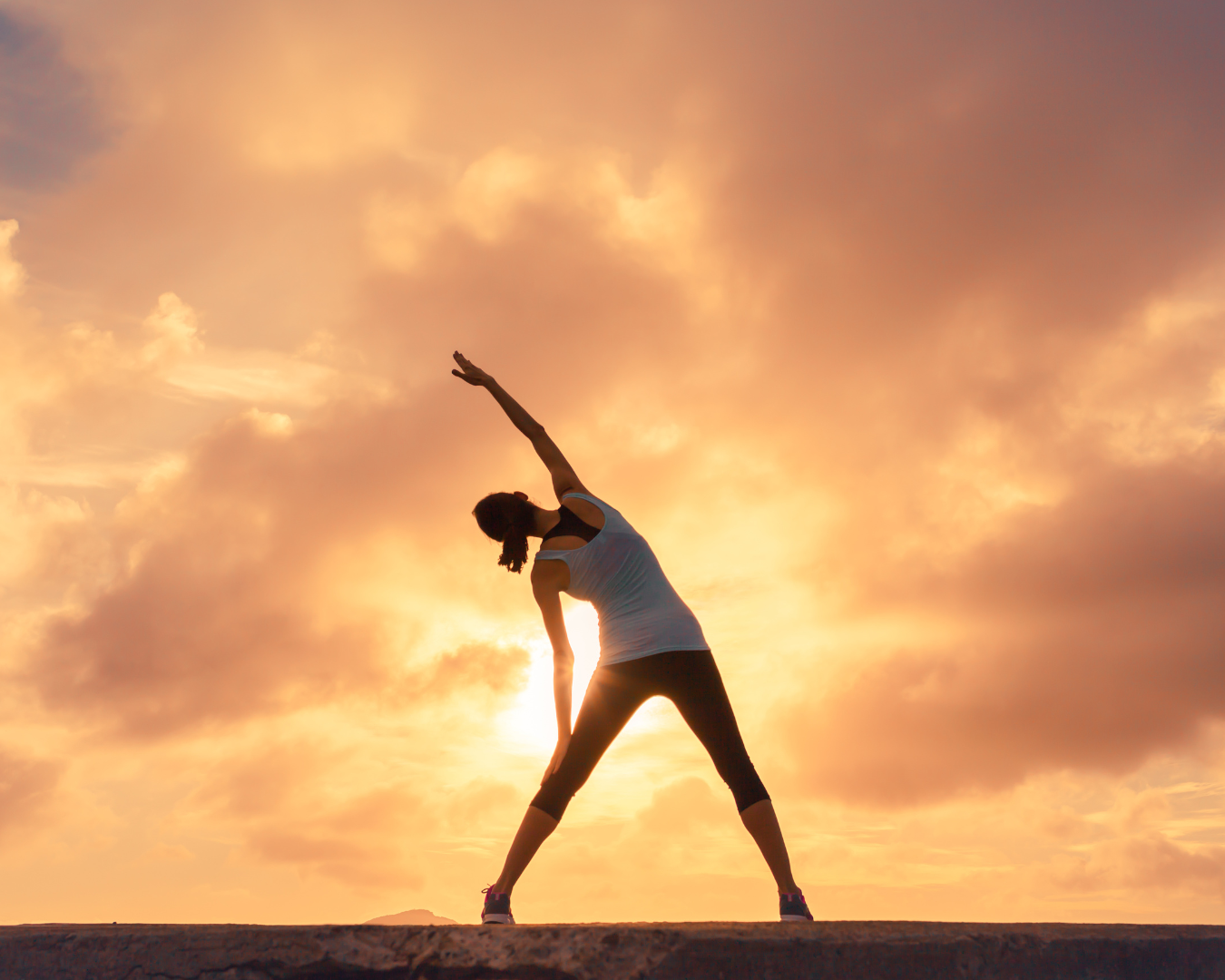 woman stretching in front of a sunset