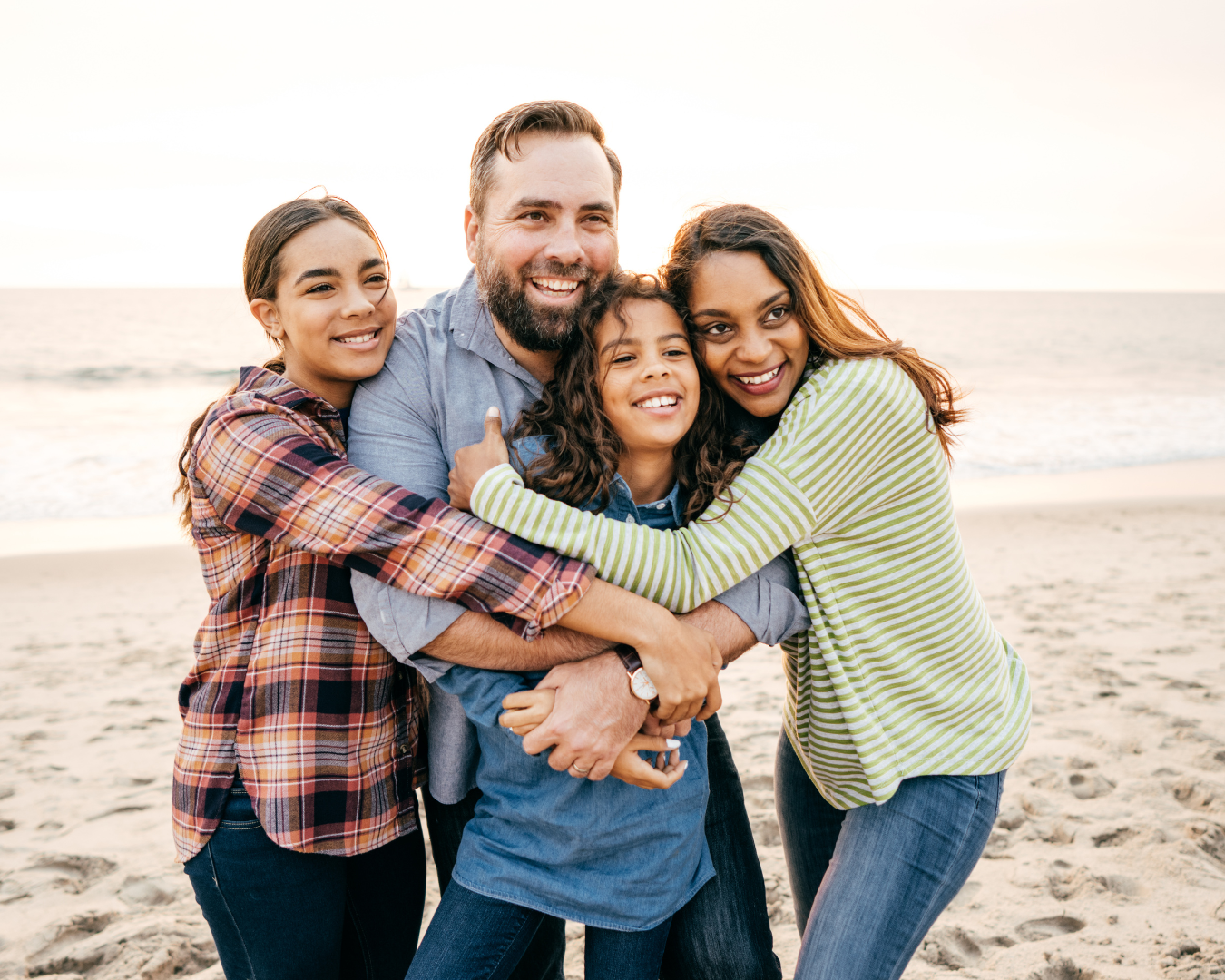 family hugging on the beach