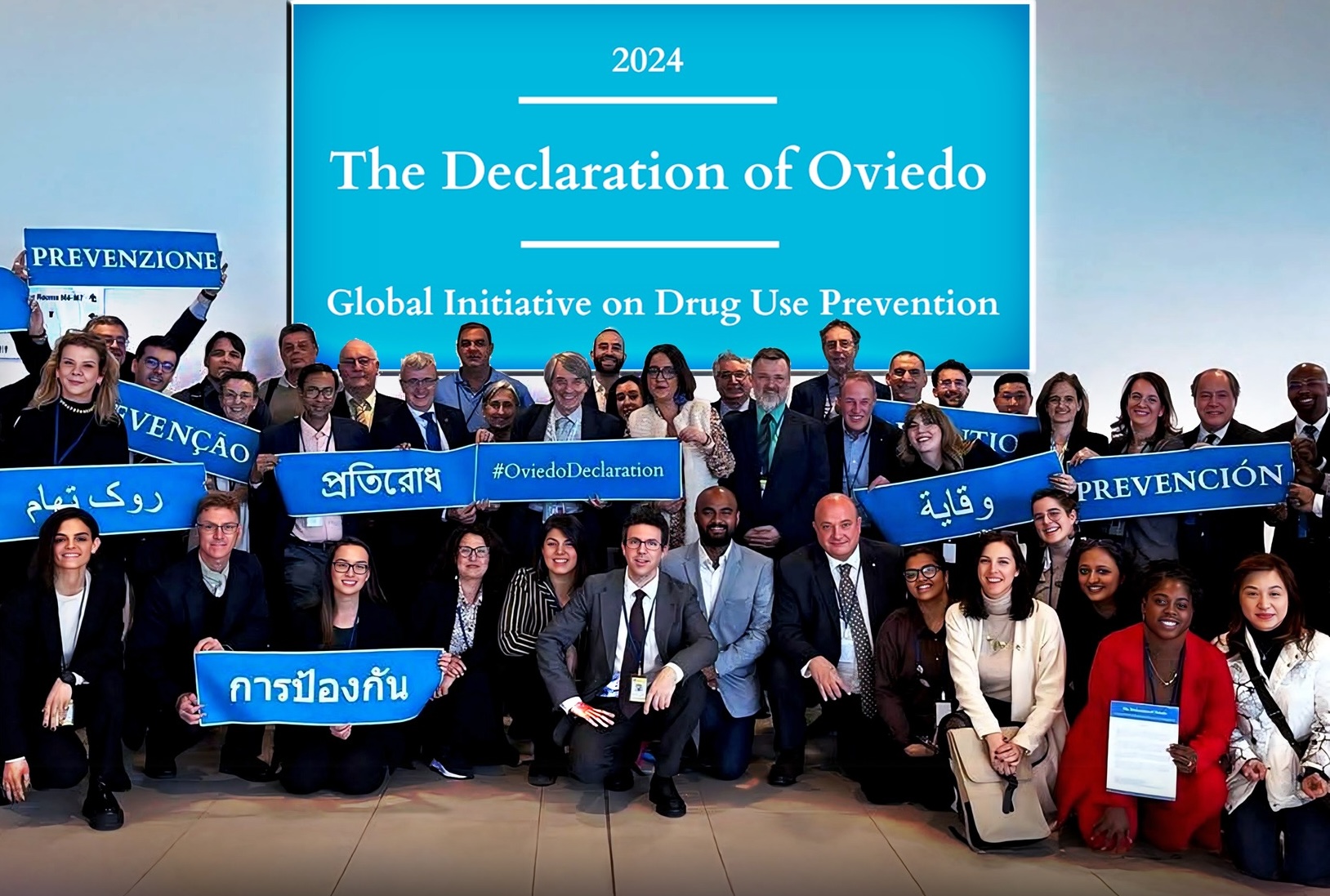 Group photo of people from around the world with signs that say "Declaration of Oviedo" in different languages