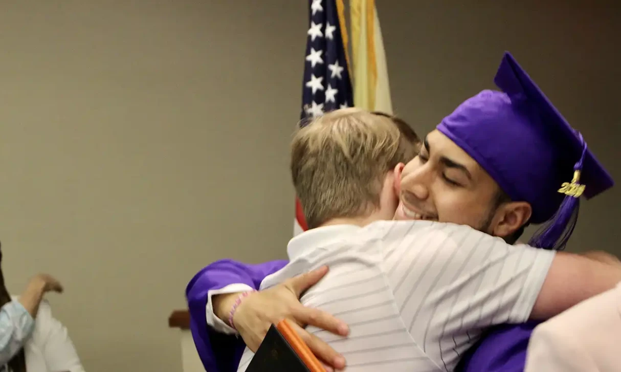Graduate in a cap and gown hugging